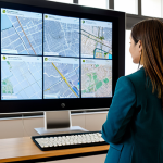 A professional female architect in a modest business blazer, standing in a contemporary urban planning office. She is attentively examining a large digital map displaying a detailed GIS overlay of Lisbon's urban zones, including PDM (Plano Diretor Municipal) and REN/RAN (Reserva Ecológica Nacional/Reserva Agrícola Nacional) designations. Blueprints and architectural models are visible on a nearby desk. The background features a blurred view of classic Portuguese buildings through a large window, suggesting a blend of old and new urban development. fully clothed, modest clothing, appropriate attire, professional dress, safe for work, appropriate content, family-friendly, perfect anatomy, correct proportions, natural pose, well-formed hands, proper finger count, natural body proportions, professional photography, high quality, sharp focus, vibrant colors, detailed.